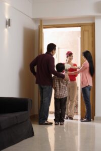 Family standing in a doorway greeting a guest