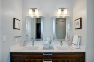 white bathroom vanity with overhead lighting and dark wood lower cabinets